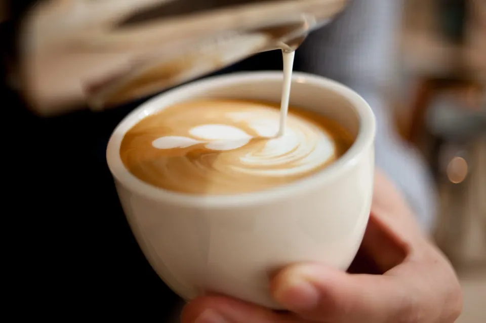 Susu dituang ke espresso membentuk latte art
